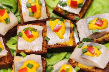 Herring finger food sandwiches with mustard and vegetables. Party snack canapes on bread with...