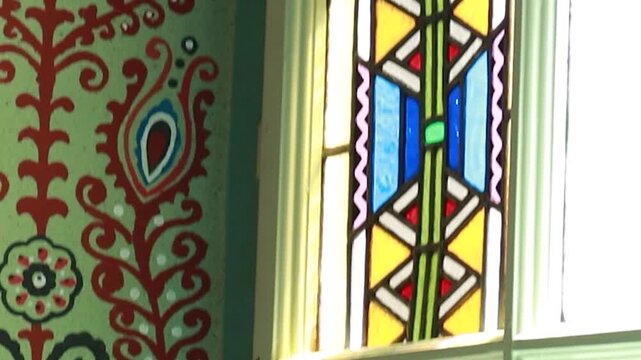 Cinematic tilt down of historic stained glass window and ornate wall in synagogue