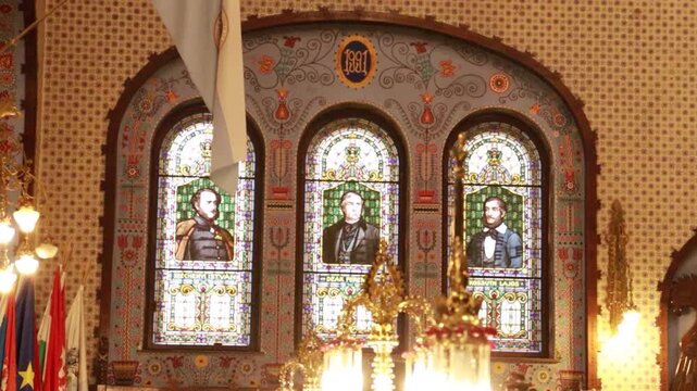 Symmetrical interior of a synagogue with stained glass windows and vintage lamps
