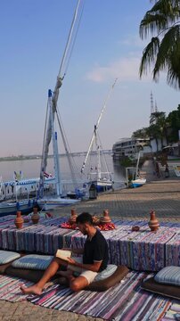 Man Sitting on Cushions by the Nile River in Luxor Egypt