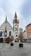 Fototapeta premium Vertical view of the historic Old Town Hall (Altes Rathaus) tower and architecture at Marienplatz square under an overcast sky in Munich, Germany.