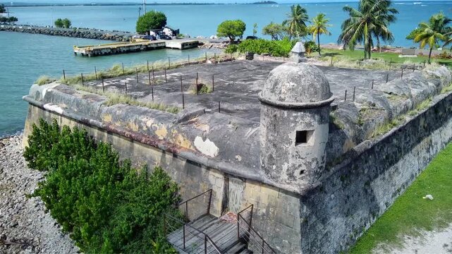 Spanish fort at a park in Puerto Rico surrounded by palm trees and the ocean. 