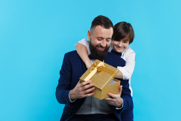 Boy greeting his father with gift on light blue background