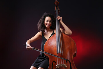 Woman playing double bass on dark red background