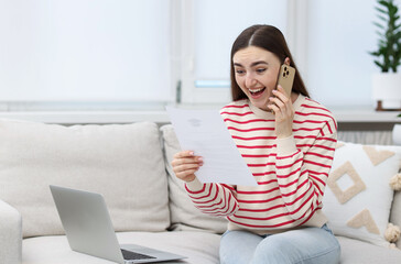 Obraz premium Happy woman with letter from university talking by smartphone on sofa at home