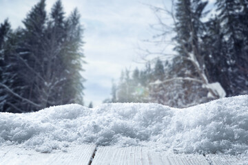 Fototapeta premium Wooden surface covered with snow against forest in winter