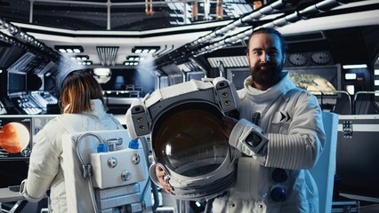 Portrait of joyful astronaut holding helmet doing scheduled operations in starship exploring deep space. Upbeat cosmonaut inspecting spacecraft hull after leaving planet © DC Studio