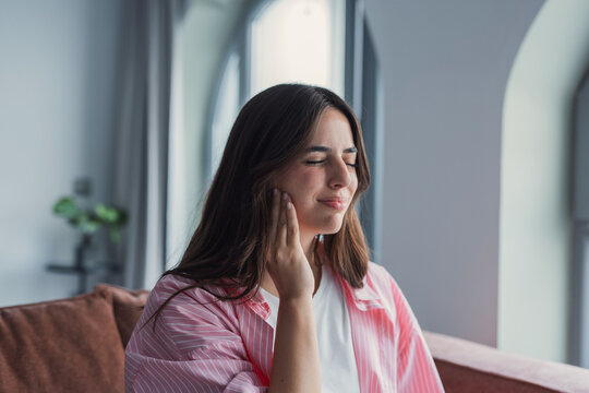 Living room, sofa and woman with mouth in pain for dental inflammation, problem or discomfort of cavity. Home, frustrated and person with sensitive tooth for wisdom teeth, emergency or oral infection