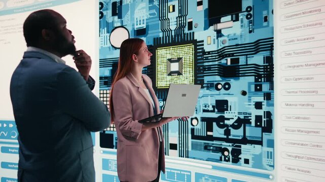 Engineering team analyzing semiconductor fabrication with laptop, looking at display. Teamworking PCB factory colleagues oversee microprocessor production with notebook, camera A