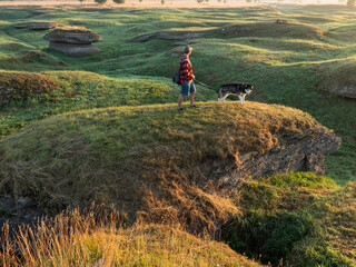 Aerial drone view of a man hiking with a husky dog in the unique karst landscape of Kostivere, Estonia. © Dmitri