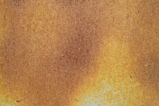 A horizontal close-up shot of a heavily oxidized metal surface, featuring a dense and uniform texture of orange and brown rust.