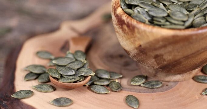 pumpkin seeds are lying on a wooden walnut board and in wooden dishes, a large number of healthy large pumpkin seeds without shells are ready for eating