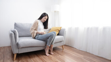Obraz premium The image depicts an interesting young woman experiencing abdominal pain, menstrual cramps, or other types of abdominal pain.