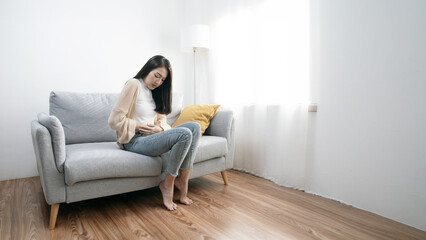 Fototapeta premium The image depicts an interesting young woman experiencing abdominal pain, menstrual cramps, or other types of abdominal pain.