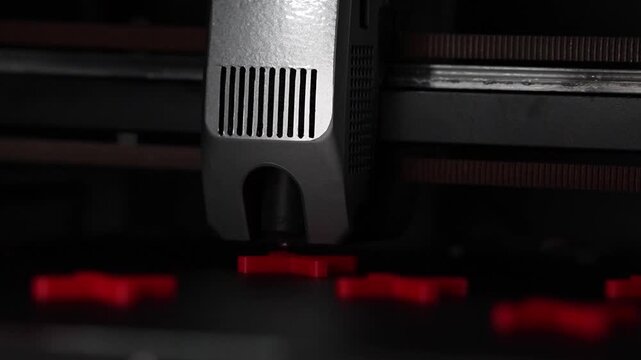 Close up of a 3D printer extruder printing red X shapes during the additive manufacturing process, detailed view of modern 3D printing technology in motion.