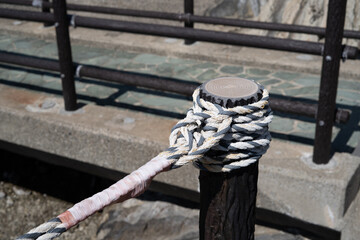 Fototapeta premium Mooring rope tied around harbor post 港の係留柱に巻かれたロープ