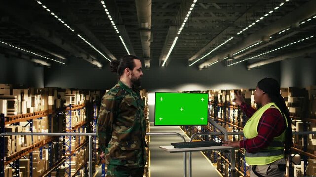 Green screen on pc monitor near military personnel operating in supply warehouse, managing shipment routes and parcel details. Secure facility supporting defense operations, command and control.