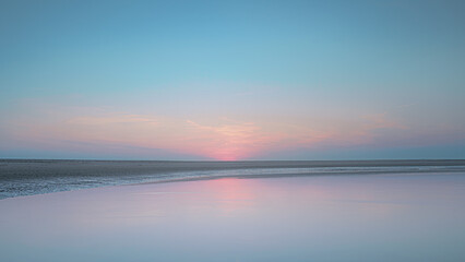 Fototapeta premium Sunset beach ocean sky reflects pastel colors.