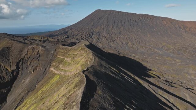 Ambrym Island volcano caldera with rugged terrain and the twin peaks of Benbow and Marum, a dramatic eroded volcanic landscape under a clear blue sky for travel and geology. Aerial drone landscape