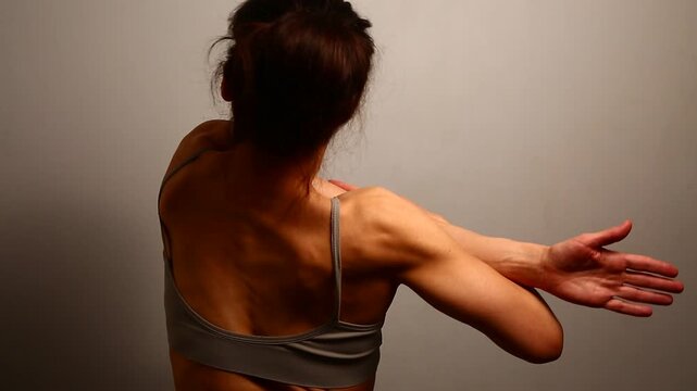 Health sport body woman doing stretching exercises for shoulders, scapula and healthy back, fitness body lifestyle. Fit naked muscles model in bra on isolated studio light with copy space. Back view
