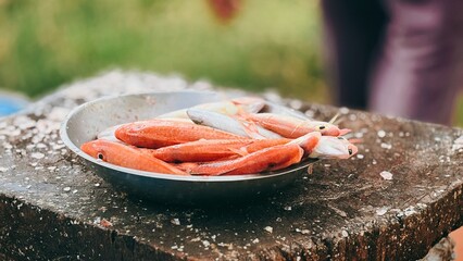 Freshly Caught Red Fish in Metal Bowl on Rustic Wooden Table with Scales, Ready for Culinary Preparation © suciramadhani