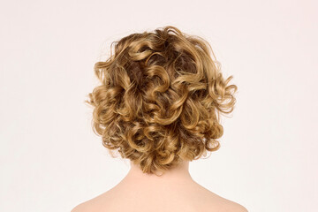 Short curly blonde hair seen from the back on neutral background