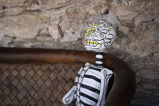 esqueleto de cart&oacute;n conmemorativo de d&iacute;a de muertos sentado en sill&oacute;n caf&eacute; r&uacute;stico