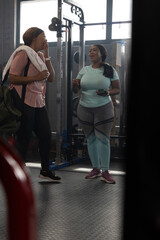 African American women wearing activewear laughing and talking near squat rack at gym with phone © wavebreak3
