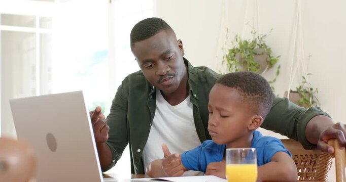 African American dad and son at home, dad opening laptop for homework, guiding counting with pencil