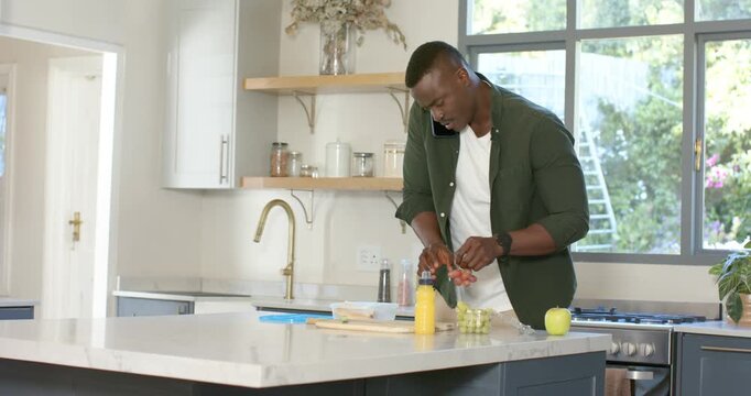 African American father and son packing lunch into backpack as son entering kitchen placing grapes