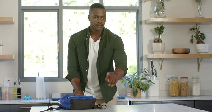African American father and son seeing dad pushing blue backpack in kitchen zipping for school