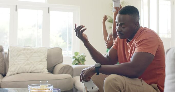 African American father and child playing game at home after child scoring, holding white gamepad