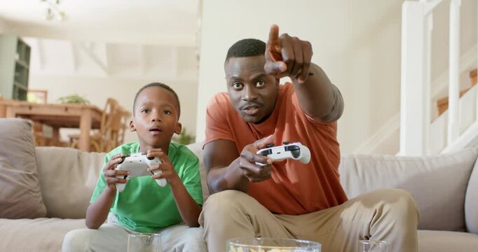 African American father and son in living-room with pads dad pointing son pressing reacting to game