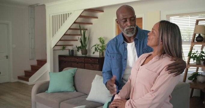 Diverse senior couple sitting on sofa while man speaking to camera, sharing message and affection