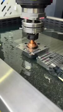 A high-angle timelapse of a precision CNC EDM machine processing a copper gear submerged in cooling fluid at a high-tech factory in China.