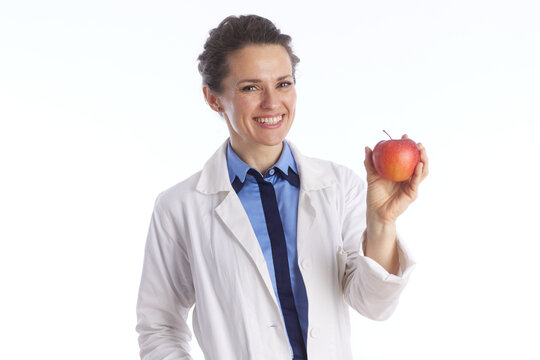 A professional female physician in a lab coat holds a red apple, representing healthy lifestyle choices, nutritional advice, and preventative medicine.