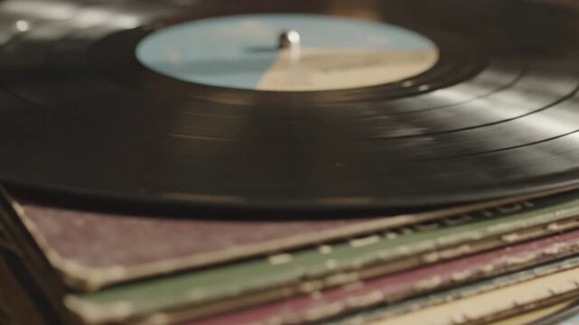 Vinyl record on top of a stack of other records, viewed from a close-up perspective in a nostalgic music environment
