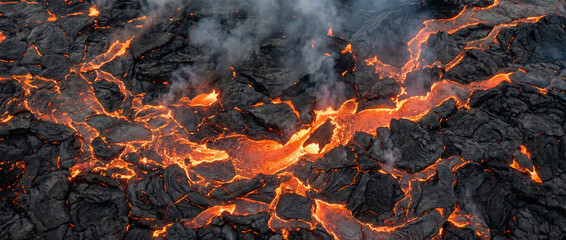 Glowing bright orange lava flowing through cracked dark volcanic rock with rising smoke.