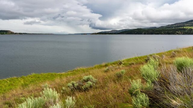 Overcast clouds moving over Canyon Ferry Lake with sagebrush and grass on the shoreline, Montana, time lapse