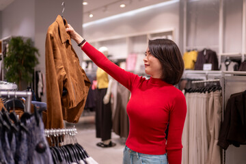 Woman shopping for clothes choosing a jacket in store