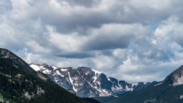 Clouds moving over snowy jagged peaks at the head of a forested mountain valley, Beartooth Mountains, Montana, time lapse