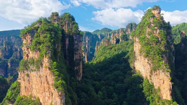 Breathtaking quartz sandstone pillars in Zhangjiajie, Hunan, China, showing dramatic mountain landscape and lush vegetation under blue sky for nature and travel concept.