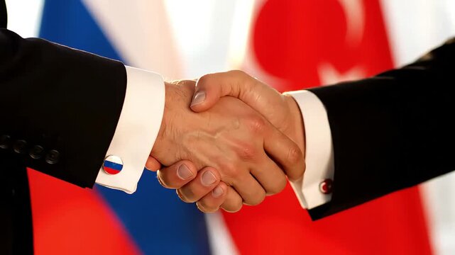 close up of a firm handshake of two men in suits against the background of the flags of russia and turkey symbolizing a peace agreement partnership diplomatic dialogue and ties