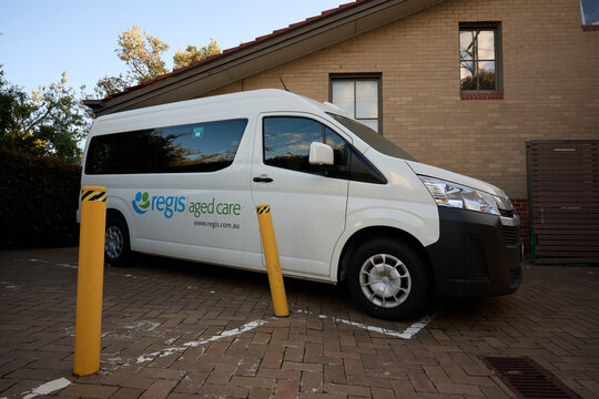 Side view of Regis Aged Care minibus van, a white Toyota HiAce, parked outside their Sandringham residential care facility