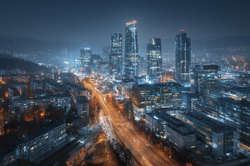 Obraz premium Aerial night skyline of modern city with illuminated building and busy street glowing warmly, showcasing urban architecture and vibrant city life under dark sky