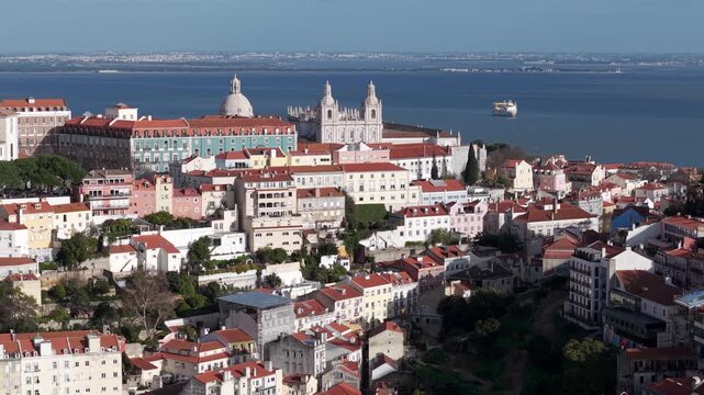 Hilltop Miradouro da Graca viewpoint with Tagus river in background, traditional Portuguese buildings with tiled roofs, Lisbon, Drone shot