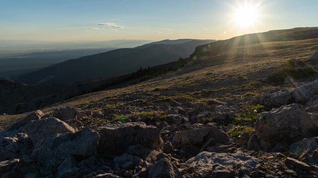Sun setting with a sunstar over a rocky mountain plateau as light fades into night, Big Snowy Mountains, Montana, time lapse