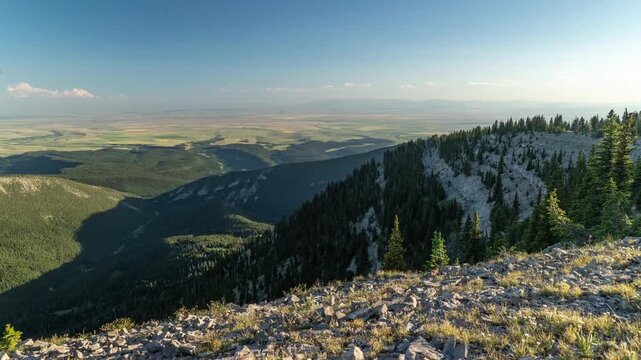 Cloud shadows moving over a forested mountain ridge and cliffs above the flat farmland plains, Big Snowy Mountains, Montana, time lapse