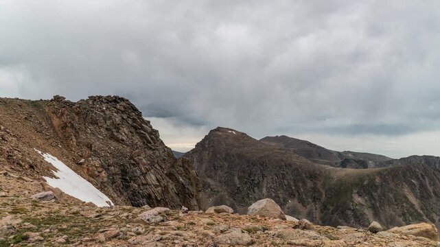 Gray clouds moving over rocky peaks and a snowfield on the Beartooth Plateau, Montana, time lapse