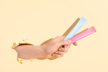 Female hand with collagen sticks visible through torn yellow paper